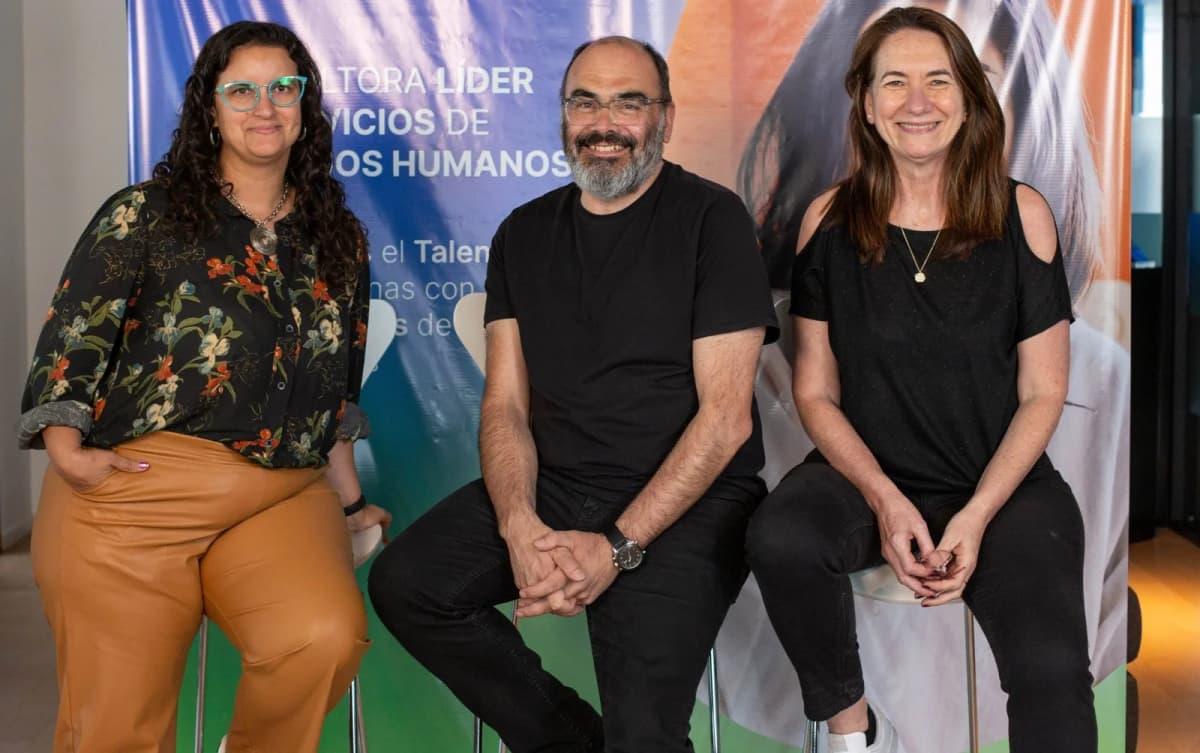Marysol Antón, Leandro Africano y Cristina Mahne, los tres socios de Multitud, sentados frente a un banner